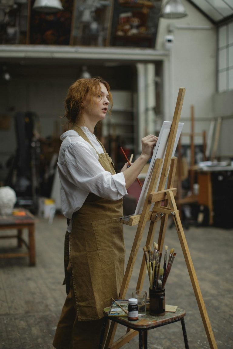 Young Woman in Brown Apron Sketching on White Cardboard